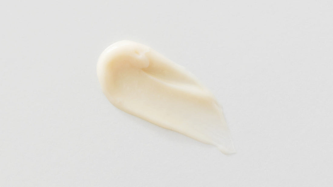Pale cream swatch on a lightly textured neutral surface.